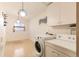 Bright laundry room features tile floors, utility sink, updated washer and dryer, plus two modern globe pendant lights at 7948 Stuart St, Westminster, CO 80030