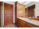 Bathroom with wood cabinets, tile floors, granite countertop, and mirror at 6980 Oak St, Arvada, CO 80004