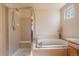 Bathroom featuring a separate shower and tub with tiled surround, along with a small window for natural light at 1758 Parkdale N Cir, Erie, CO 80516