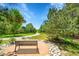 A peaceful backyard retreat featuring a shaded bench, decorative rocks, and mature trees along a walking path at 20530 Parker Vista Cir, Parker, CO 80138