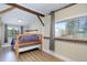 Bright bedroom with wood floors, exposed wood beam, and windows showcasing outdoor views at 6743 Wild Rose Ln, Evergreen, CO 80439
