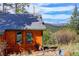 Charming log cabin home featuring window views, set against a backdrop of mountains and lush green trees at 6743 Wild Rose Ln, Evergreen, CO 80439