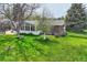 Spacious backyard with a well-kept lawn, mature trees, and a sunroom attached to the home at 798 Alkire St, Lakewood, CO 80401