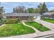 Charming brick home featuring a well-manicured lawn, curved walkway, and mature landscaping at 798 Alkire St, Lakewood, CO 80401