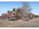 Apartment building exterior showcasing brick and gray siding with ample parking and partial snow covering at 14211 E 1St Dr # 308, Aurora, CO 80011