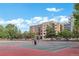 Outdoor tennis courts adjacent to modern buildings, surrounded by trees, under a blue sky at 4215 W Byron Pl, Denver, CO 80212
