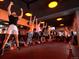 Indoor workout class of people raising their arms in a fitness studio with orange lighting at 4215 W Byron Pl, Denver, CO 80212
