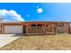 Charming brick home with a covered front porch and attached garage on a sunny day at 7720 Kendall St, Arvada, CO 80003