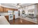 Kitchen with oak cabinets, white appliances, opening to carpeted living space at 7720 Kendall St, Arvada, CO 80003