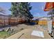 View of the backyard with a concrete pad, large tree, and wooden fence at 8221 Ralph Ln, Denver, CO 80221