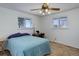 Bright bedroom featuring a ceiling fan, two windows, and cozy blue bedspread at 8221 Ralph Ln, Denver, CO 80221