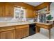 Sunlit kitchen showcasing wood cabinets, tile backsplash, and sleek black dishwasher at 8221 Ralph Ln, Denver, CO 80221
