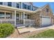 Inviting front porch with white railings, gray siding, a decorative wreath, and manicured landscaping at 22197 E Stroll Ave, Parker, CO 80138