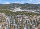 A distant view showcasing a charming two-story house nestled in a wintery, tree-filled landscape at 28592 Hummingbird Hill Rd, Conifer, CO 80433