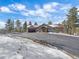 Charming front exterior with large driveway, porte-cochere, well-manicured lawn, and an attached three-car garage at 28592 Hummingbird Hill Rd, Conifer, CO 80433