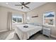 Well-lit bedroom with a ceiling fan, two windows with neighborhood views, and neutral tones throughout at 1530 Terry St, Longmont, CO 80501