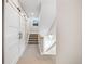 Hallway with sliding barn door leading to carpeted stairs with wood railing and decorated with stylish wall art at 1530 Terry St, Longmont, CO 80501