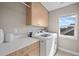 Bright laundry room featuring a modern washer and dryer, ample storage cabinets, and a window for natural light at 1530 Terry St, Longmont, CO 80501