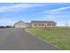 Tan home with attached garage, red shutters, and long gravel driveway at 14551 N Harback Rd, Keenesburg, CO 80643