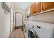 Well-lit laundry room featuring modern white washer and dryer, wooden cabinets and hanging rack at 14551 N Harback Rd, Keenesburg, CO 80643