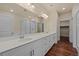 Bright bathroom features double vanity with sleek white cabinets, quartz countertop, and framed mirror at 152 Ambrose St, Erie, CO 80516