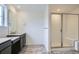 Bright bathroom with glass enclosed shower, gray tile floor, and dark vanity with quartz countertop at 4588 Thistle Dr, Brighton, CO 80601