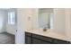 Bathroom with dark vanity and quartz countertop, leading into a bedroom with gray carpet at 4588 Thistle Dr, Brighton, CO 80601