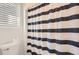 Cozy bathroom features a toilet with a striped shower curtain and natural light from window at 417 S Ouray St, Aurora, CO 80017