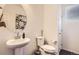 This half bath showcases a stylish pedestal sink, a round mirror, and modern fixtures at 417 S Ouray St, Aurora, CO 80017