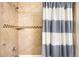 Tiled shower features neutral stone tile work, built-in shelf, and a blue striped shower curtain at 20389 E Powers Pl, Centennial, CO 80015
