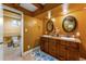 Basement bathroom with dual sinks, wood cabinets, and a toilet at 1395 Bellaire St, Denver, CO 80220