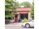 Street view featuring a coffee shop with a red door and awning, framed by lush trees at 500 S Pennsylvania St # 520, Denver, CO 80209