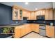 A stylish kitchenette featuring sleek black countertops, natural wood cabinets, and modern stainless steel microwave and fridge at 9924 Silver Maple Way, Highlands Ranch, CO 80129