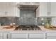 Close-up of a gas range and stainless steel range hood with gray subway tile backsplash at 11821 Discovery Ln, Parker, CO 80138