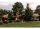 Beautiful home with a red tile roof surrounded by lush landscaping and mature trees at 1621 Baneberry Ln, Golden, CO 80401