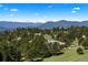 Beautiful mountain views surround a home nestled amongst towering pine trees and other high-end properties at 1621 Baneberry Ln, Golden, CO 80401