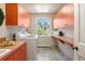 Bright laundry room with orange cabinetry, a utility sink, and a washer/dryer set at 1621 Baneberry Ln, Golden, CO 80401