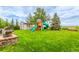 Well-maintained backyard featuring a playset, shed, and expansive green lawn at 12330 Village E Cir, Commerce City, CO 80603