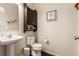 Powder room with pedestal sink, wood cabinet and decor at 12330 Village E Cir, Commerce City, CO 80603