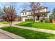 Charming home boasts a large front yard, and manicured lawn, with mature trees and lush landscaping at 12330 Village E Cir, Commerce City, CO 80603