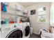 Functional laundry room with washer, dryer, and open shelving for storage at 12330 Village E Cir, Commerce City, CO 80603