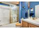 Well-lit bathroom includes a glass-enclosed shower, vanity, and decorative blue walls at 5155 W Quincy Ave # 101, Denver, CO 80236