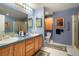 Bathroom featuring double sinks, framed mirrors, and a glass-enclosed shower at 5155 W Quincy Ave # 101, Denver, CO 80236