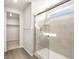 Bathroom featuring a glass enclosed shower, wood look floors, towel rack and large walk-in closet with storage at 6068 Corral St, Brighton, CO 80601