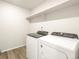 Functional laundry room featuring modern washer and dryer, white walls, wood-look floors and an above shelf at 6068 Corral St, Brighton, CO 80601