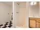 Modest bathroom featuring a standing shower, toilet, and small vanity with black and white tile floor at 4350 S Delaware St, Englewood, CO 80110