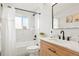 Bright bathroom featuring marble tiling, modern vanity, and a shower-tub combination at 6163 W 76Th Ave, Arvada, CO 80003