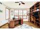 Bright home office featuring a large desk, built-in bookshelf, and expansive windows at 2253 Augusta Dr, Evergreen, CO 80439