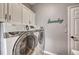Clean laundry room with front loading machines, cabinets for storage, and a modern look at 570 Stonemont Dr, Castle Pines, CO 80108