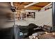 Basement is a sleeping area, with exposed ceiling, disorganized storage shelves, and a dark sofa at 5211 Dover St, Arvada, CO 80002